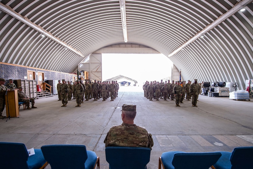 Members of the 35th Combat Aviation Brigade, Missouri Army National Guard, and the 244th Expeditionary Combat Aviation Brigade, U.S. Army Reserve, stand ready during a transfer of authority ceremony in an aircraft hangar in Taji, Iraq, May 1, 2019.  The 35th CAB and 244th ECAB support Combined Joint Task Force – Operation Inherent Resolve and Operation Spartan Shield.  CJTF-OIR works with partner forces to defeat Daesh in designated areas and set conditions for follow-on operations to increase regional stability.