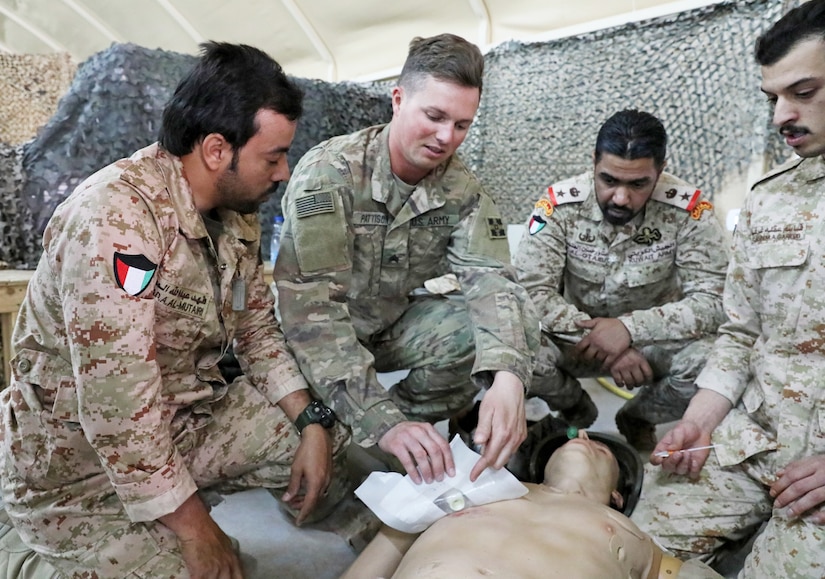 U.S. Army Sgt. Curtis Pattinson, center, a medic with 64th Brigade Support Battalion, 3rd Armored Brigade Combat Team, 4th Infantry Division, Task Force Spartan, conducts joint medical training at Camp Buehring, Kuwait, with Kuwaiti Land Forces Soldiers from the 11th Engineer Battalion on April 3, 2019. The Soldiers worked together to practice basic combat lifesaver skills, such as placing a chest seal.