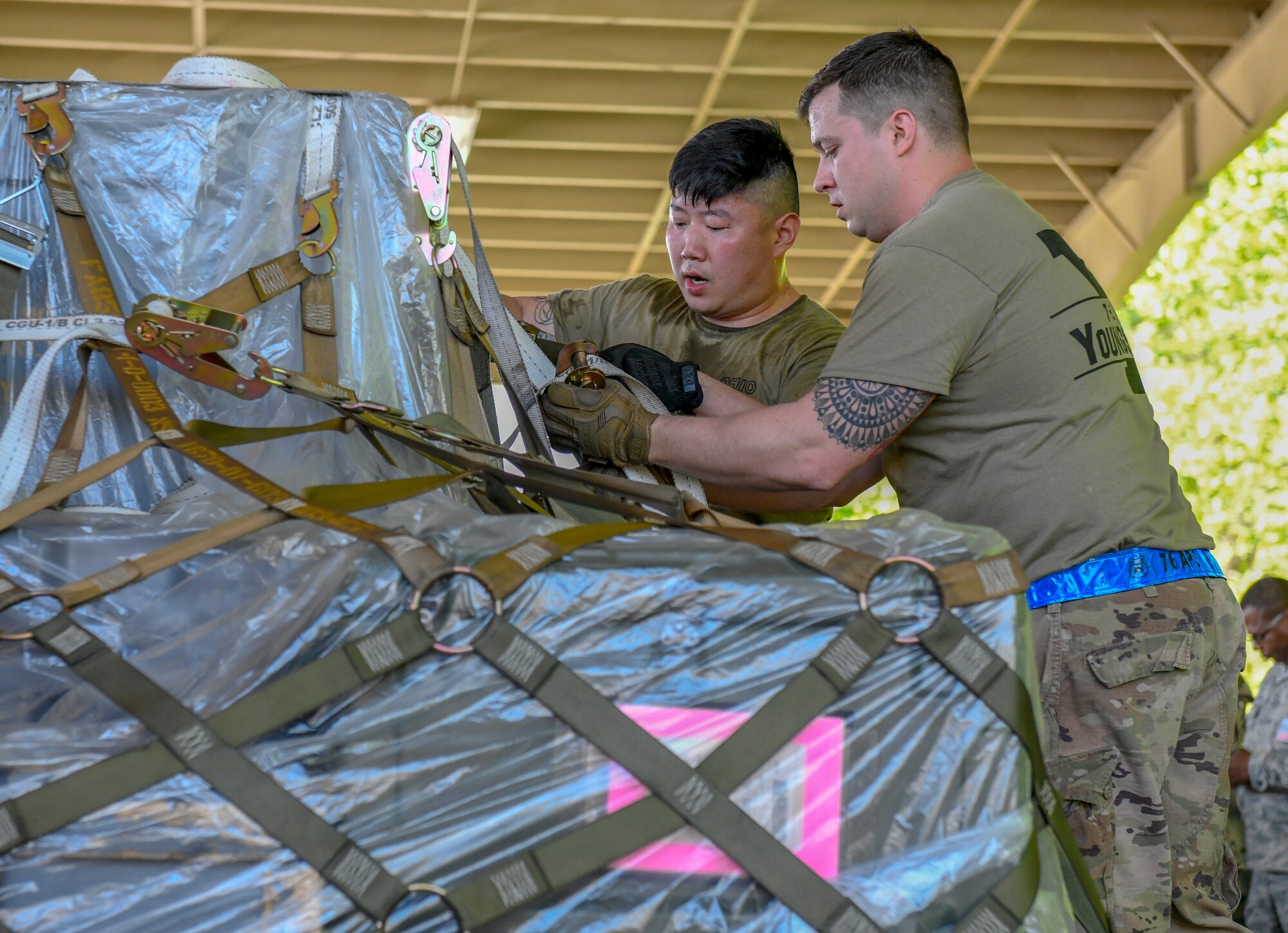Master Sgt. Tae Choe (left), a ramp services supervisor, Master Sgt. Zach Dunkin (right), NCO in charge of load planning, and Tech. Sgt. Michael Nippers Jr. (right), all assigned to the 76th Aerial Port Squadron, tie down cargo for the pallet build-up event at the Port Dawg Challenge April 24, 2019.