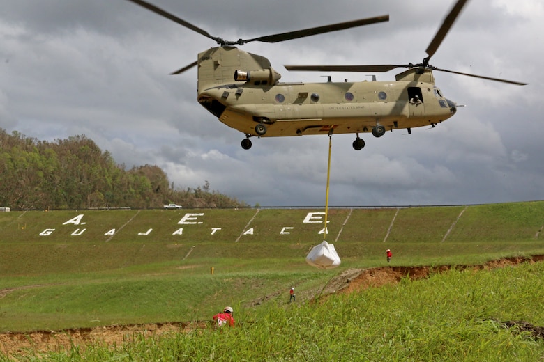 Chinook helicopter places a large sand bag on the spillway