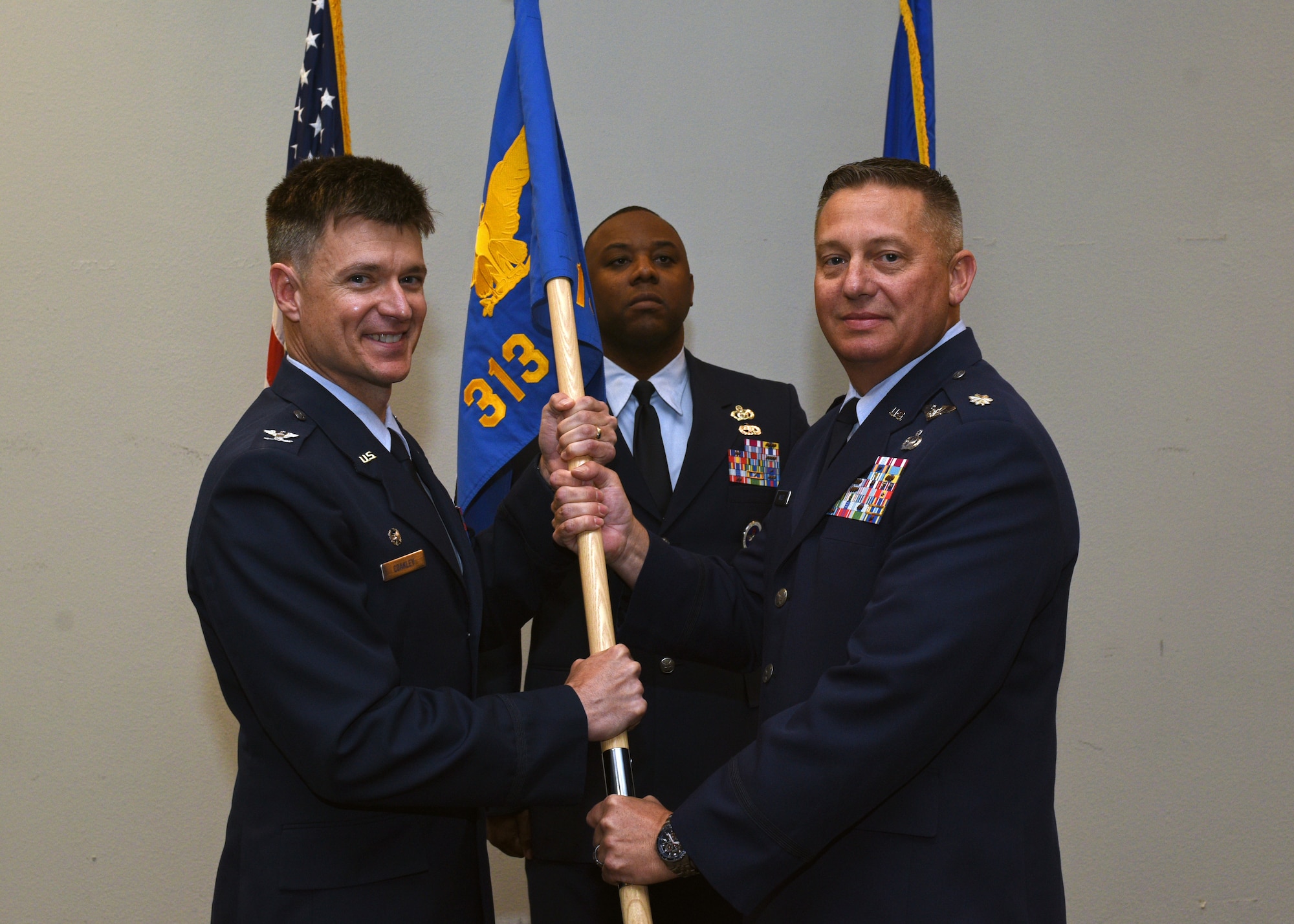 U.S. Air Force Col. Thomas Coakley, 17th Training Group commander, passes the 313th Training Squadron guidon to Lt. Col. Herbert Millet III during a change-of-command ceremony at the event center on Goodfellow Air Force Base, Texas, May 10, 2019. Millet assumed command of the 313th Training Squadron from Lt. Col. David Sarabia during the change of command ceremony. (U.S. Air Force photo by Airman 1st Class Robyn Hunsinger/released)