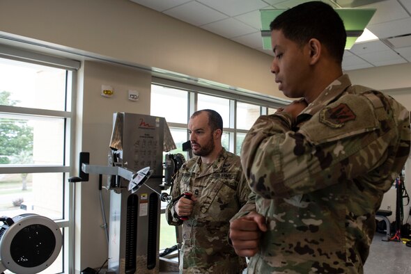 U.S. Army Sgt. 1st Class David Bedford, U.S. Army Central Command explosive ordnance disposal noncommissioned officer, uses a workout machine while U.S. Air Force Staff Sgt. Marcos Davis, 20th Medical Operations Squadron physical therapy technician, demonstrates how to perform the movement at Shaw Air Force Base, S.C., May 10, 2019.