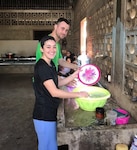 A smiling man and woman wash dishes