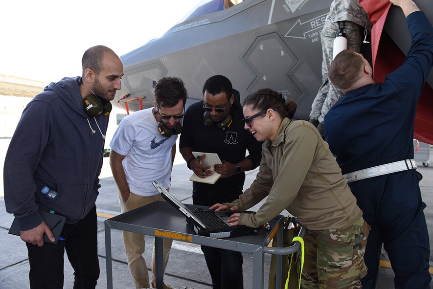 Ron Golan, Peter Wallace, and DeMarcus Townsend from Detachment 12 at Hanscom Air Force Base, Mass., work with Staff Sgt. Samantha Buxton, dedicated crew chief with the 57th Wing’s Bolt Aircraft Maintenance Unit at Nellis Air Force Base, Nev., on the Nellis flightline, near an F-35 Lightning II Joint Strike Fighter April 10, 2019. The “Mad Hatter” team from Det. 12 is learning how maintainers navigate technical orders while working on the flightline. (U.S. Air Force photo by Airman 1st Class Bailee Darbaise)