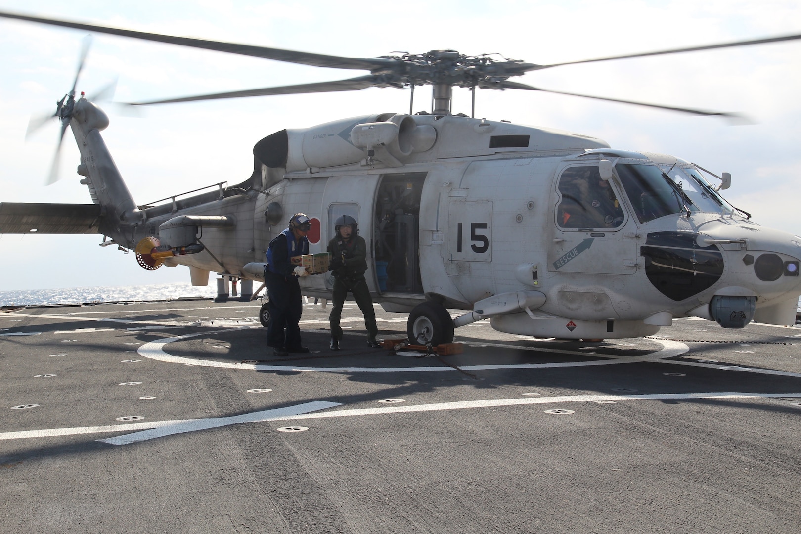 Sailor assigned to USS Curtis Wilbur receives food from Japan Maritime Self-Defense Force helicopter air crewman for Acquisition and Cross Servicing
Agreement logistics exchange during Keen Sword 19, Philippine Sea, October 31, 2018 (U.S. Navy/Emily Cooper)