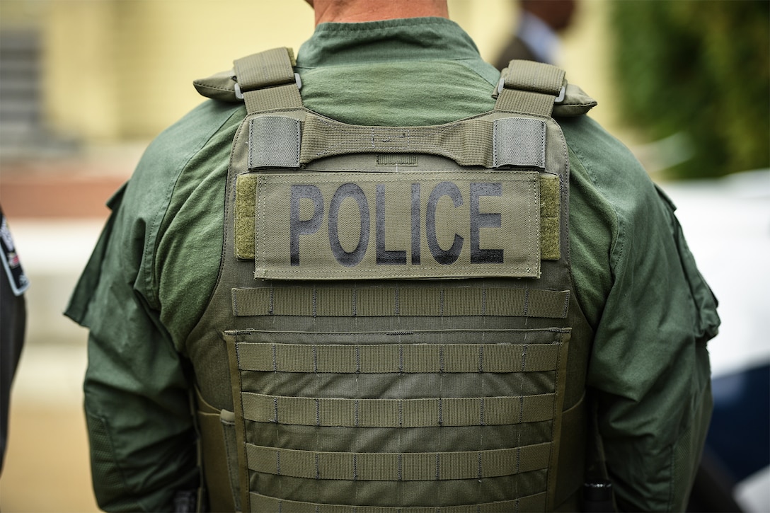 The back of a police officer’s tactical vest bears the word “police.”