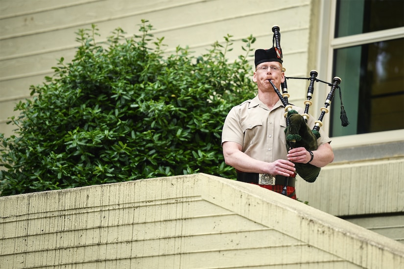 A musician plays bagpipes at the top of a set of stairs.