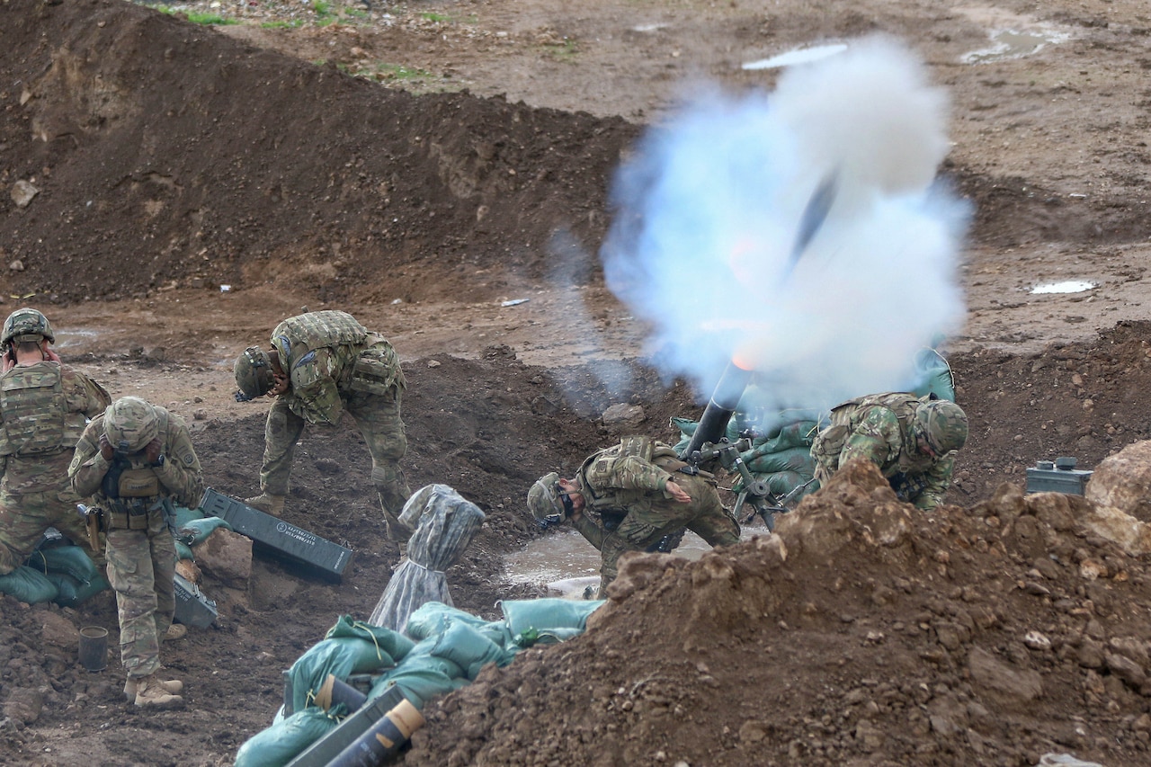 Soldiers fire mortars in the dirt.
