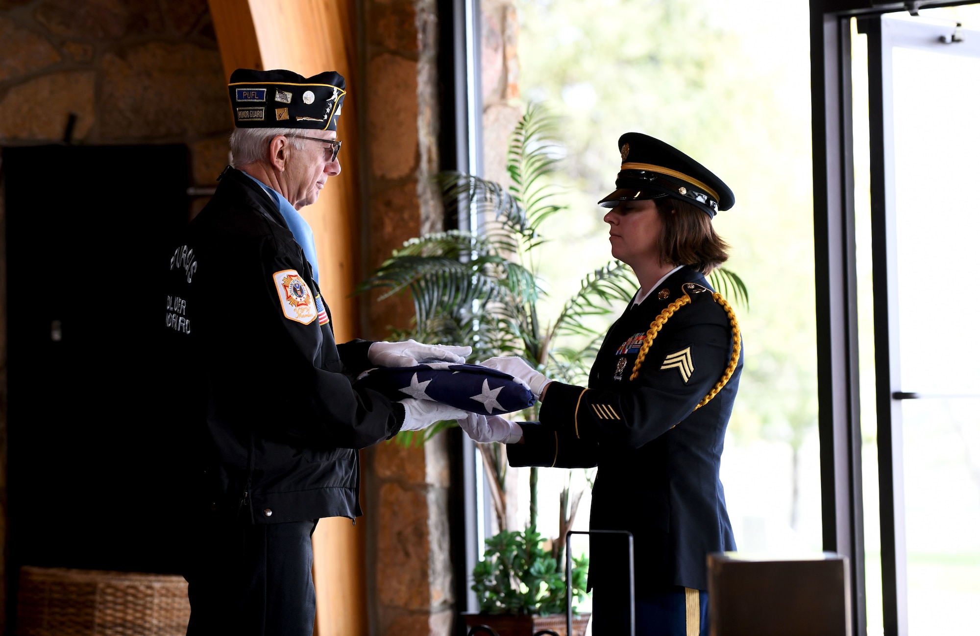 A South Dakota Army National Guardsman hands a folded burial flag over to a member of the Sturgis Honor Guard before it is presented to the family of former Pfc. Carroll E. Lonas at the Black Hills National Cemetery in Sturgis, S.D., May 9, 2019. Lonas was captured by the Germans during World War II and was detained for 14 months prior to his escape. He hiked roughly 1,100 miles until he reached friendly territory. (U.S.  Air Force photo by Airman 1st Class Christina Bennett)