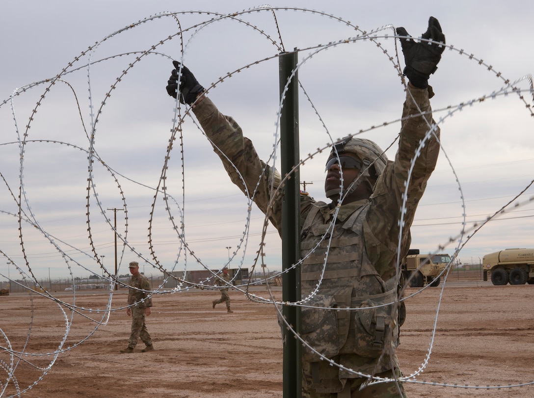 Soldier with 541st Engineer Company, Special Purpose Marine Air-Ground Task Force 7, moves concertina wire over stake on practice barricade at Naval Air Facility El Centro in California, December 4, 2018 (U.S. Marine Corps/Asia J. Sorenson)