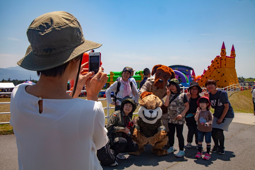キャンプ富士で5月11日に行われたフレンドシップフェスティバルで、アメリカのキャラクターと一緒に写真撮影をする日本人家族。キャンプ富士のフェスティバルには毎年大勢の地域住民が来場し、日米友好を満喫しています。