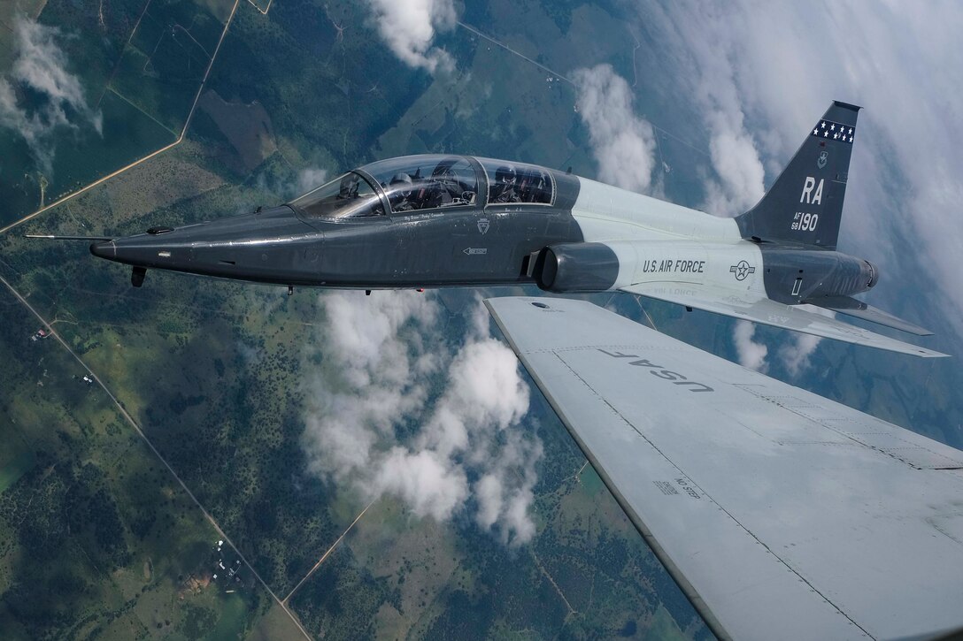 A plane flying through the sky over land.