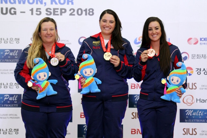 Three women stand on a winner’s podium.