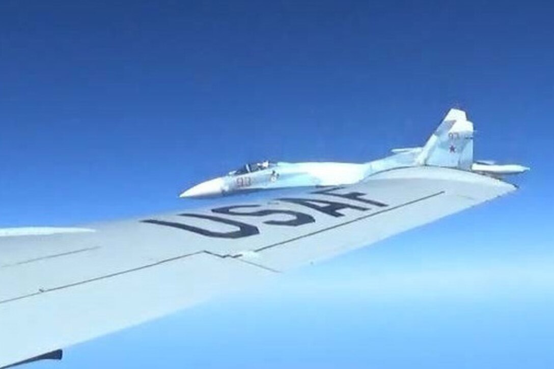 A jet flies close to another aircraft’s wing.