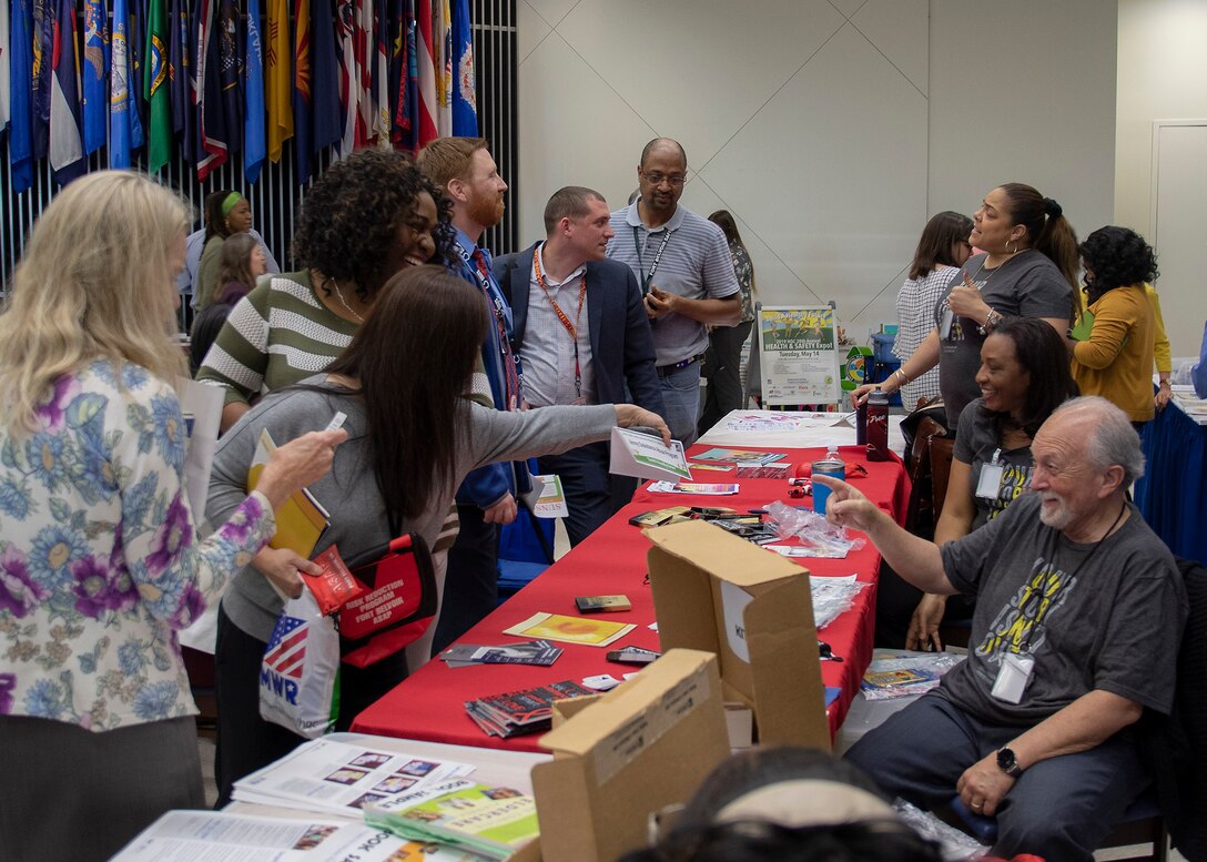 women and men visit vendor tables during the 20th Health and Safety Expo in the HQC Café, May 14.