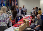 women and men visit vendor tables during the 20th Health and Safety Expo in the HQC Café, May 14.