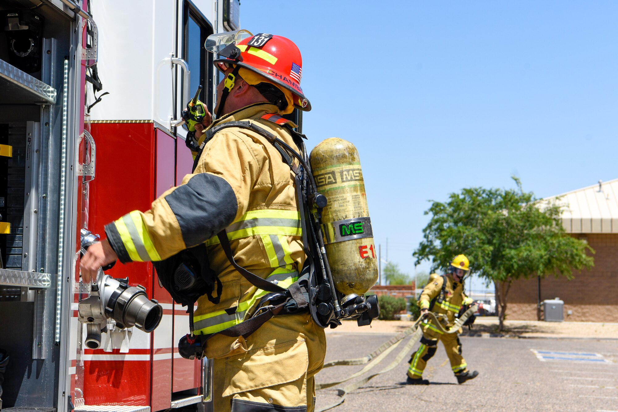 Firefighters from the west valley prepare to lay hose for a joint training exercise May 3, 2019, at Luke Air Force Base, Ariz. The multi-company standard training focused on meeting and excelling in the benchmarks of consistency in fire operations and stretching hose lines to upper levels of buildings. (U.S. Air Force photo by Airman 1st Class Zoie Cox)
