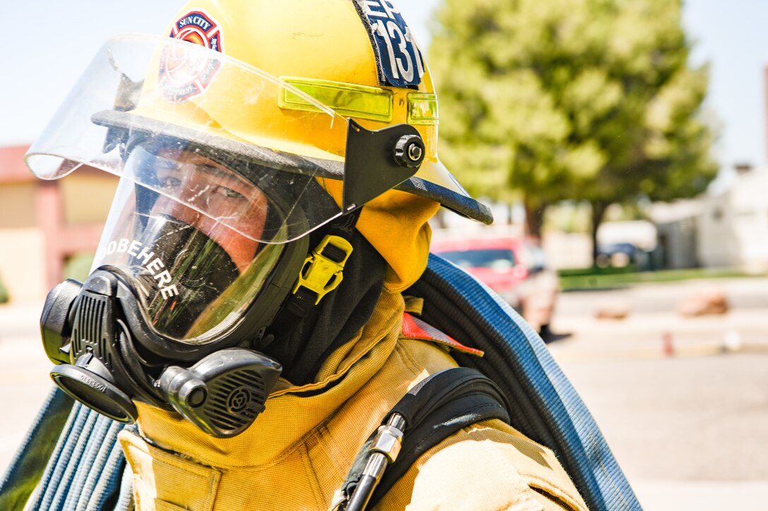 A firefighter from the Sun City Fire Department lugs a hose up a flight of stairs during a joint training exercise May 3, 2019, at Luke Air Force Base, Ariz. The exercise tested the ability of different fire departments to work together successfully when responding to emergencies. (U.S. Air Force photo by Airman 1st Class Zoie Cox)