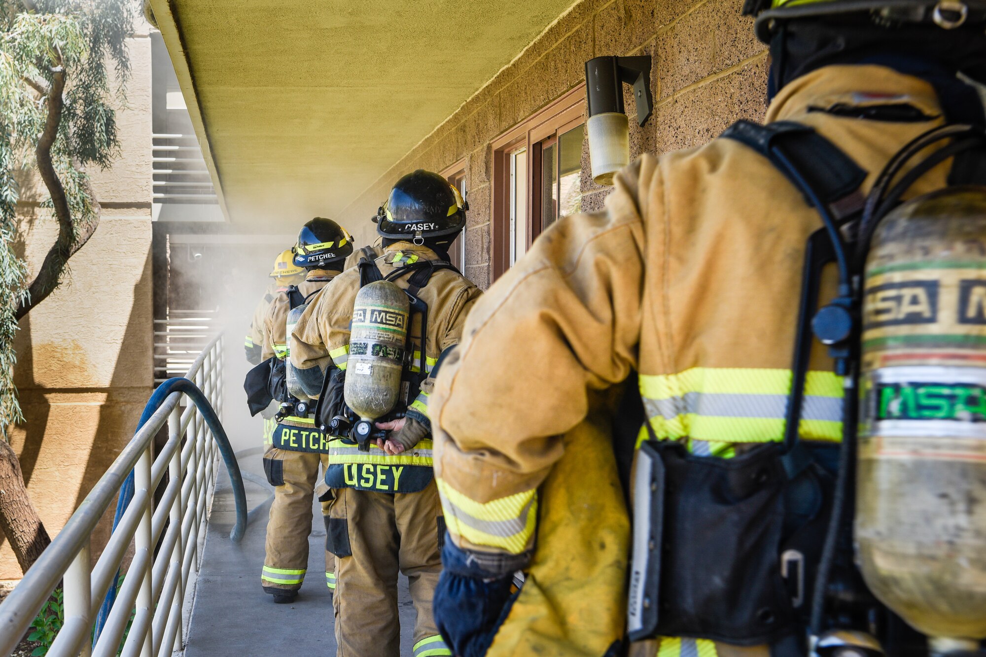 A line of firefighters prepare to enter a room during a joint training exercise May 3, 2019, at Luke Air Force Base, Ariz. The Luke AFB Fire Department responds to emergencies in the local community while local fire departments respond to emergency calls on base. Multi-company standard trainings such as these help firefighters practice basic operating procedures together so they can be effectively used in real world situations. (U.S. Air Force photo by Airman 1st Class Zoie Cox)