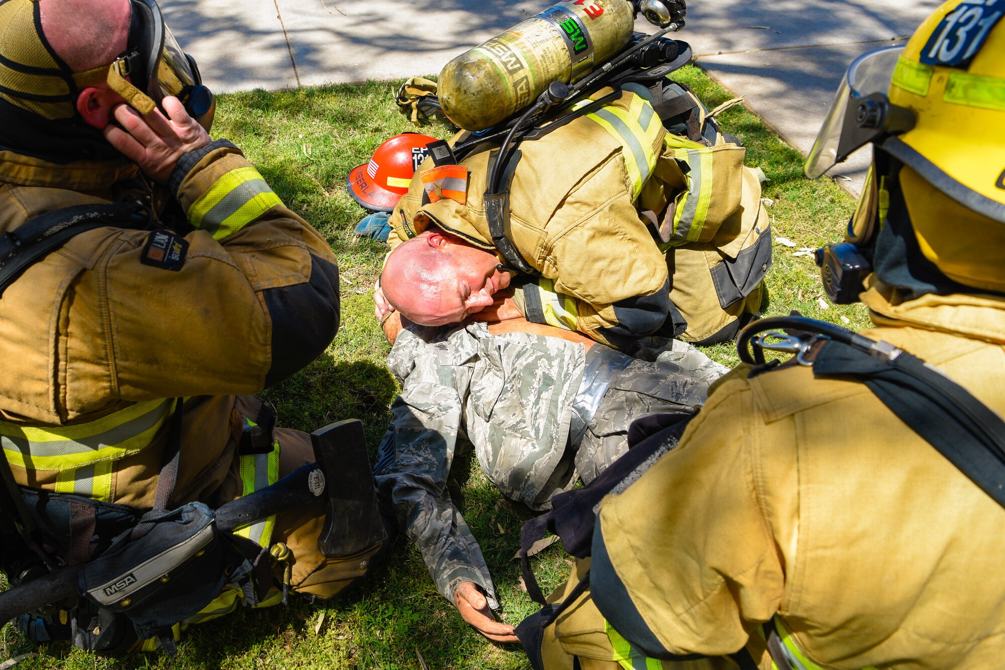 Firefighters huddle around a mannequin while simulating CPR during a joint training exercise May 3, 2019, at Luke Air Force Base, Ariz. The multi-company standard training mimicked a motel fire where the firefighters had to subdue the fire and tend to the injured preparing for transport. (U.S. Air Force photo by Airman 1st Class Zoie Cox)