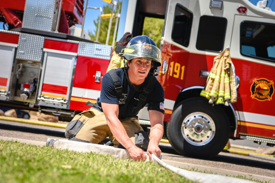 An Arizona Fire Medical Authority firefighter rolls a hose during a joint training exercise May 3, 2019, at Luke Air Force Base, Ariz. The multi-company standard training focused on meeting and excelling in the benchmarks of consistency in fire operations and stretching hose lines to upper levels of buildings. (U.S. Air Force photo by Airman 1st Class Zoie Cox)