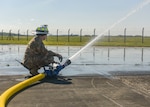 U.S. Air Force Master Sgt. Jeremiah Gates, 100th Civil Engineer Squadron assistant chief of training, sprays water across the pavement at RAF Mildenhall, England, May 15, 2019. The fire department provided water to simulate spilled fuel for the exercise. The fuel spill exercise was conducted to test the base’s response and recovery capabilities. (U.S. Air Force photo by Airman 1st Class Joseph Barron)