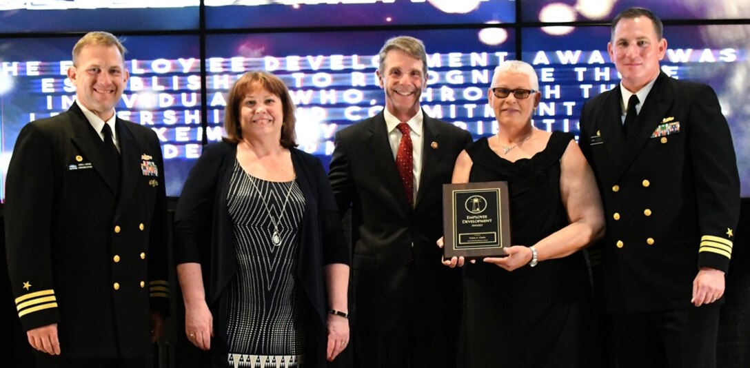 IMAGE: Fredericksburg, Va. (May 10, 2019) – Delois Clarke holds the Employee Development Award moments after receiving it from Naval Surface Warfare Center Dahlgren Division (NSWCDD) leadership at the command’s annual honor awards ceremony. Clarke was recognized for her exemplary execution as a leader across the organization. Her mentorship and persistence has led to a continuous pipeline of highly skilled personnel, enabling the successful maintenance of a key national capability. Standing left to right: NSWCDD Dam Neck Activity Commanding Officer Cmdr. Andrew Hoffman; NSWCDD Deputy Technical Director Angela Beach; U.S. Rep. Rob Wittman; Clarke; and NSWCDD Commanding Officer Cmdr. Stephen ‘Casey’ Plew.  (U.S. Navy photo/Released)
