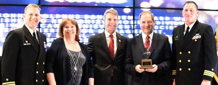 IMAGE: FREDERICKSBURG, Va. (May 10, 2019) – Brian Seay holds the John Adolphus Dahlgren Award moments after receiving it from Naval Surface Warfare Center Dahlgren Division (NSWCDD) leadership at the command’s annual honor awards ceremony. The award was granted to Seay for his innovative technical contributions and proven ability as a director. Seay was recognized for his ability to organize, motivate, develop strategies and lead teams to meet complex combat system goals while adjusting to continuously changing requirements, schedules and budgets. Standing left to right: NSWCDD Dam Neck Activity Commanding Officer Cmdr. Andrew Hoffman; NSWCDD Deputy Technical Director Angela Beach; U.S. Rep. Rob Wittman; Seay; and NSWCDD Commanding Officer Cmdr. Stephen ‘Casey’ Plew.  (U.S. Navy photo/Released)