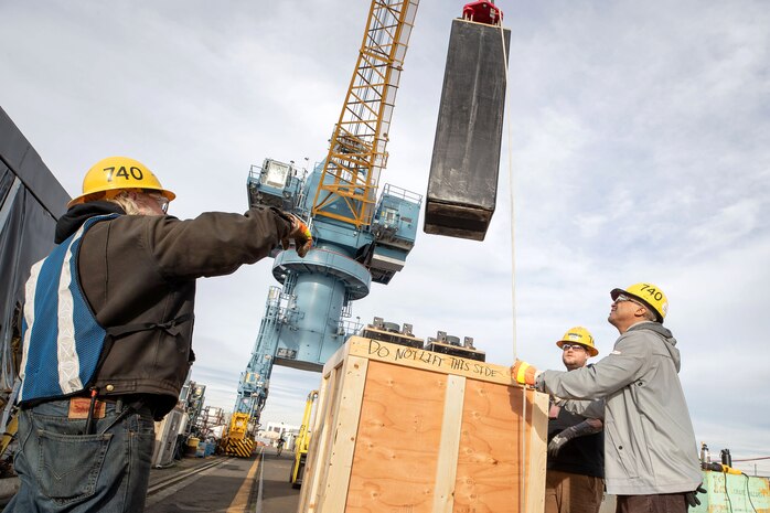 Bruce Robertson left, Steven Dent and Senteil Andrews, PSNS & IMF Code 740 riggers, land the battery cell removed from USS Bremerton (SSN 698).