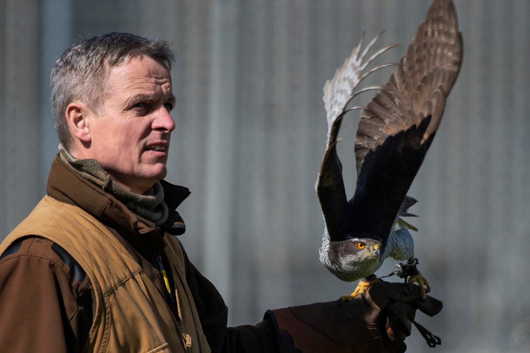 A man holds a big bird in his hand.