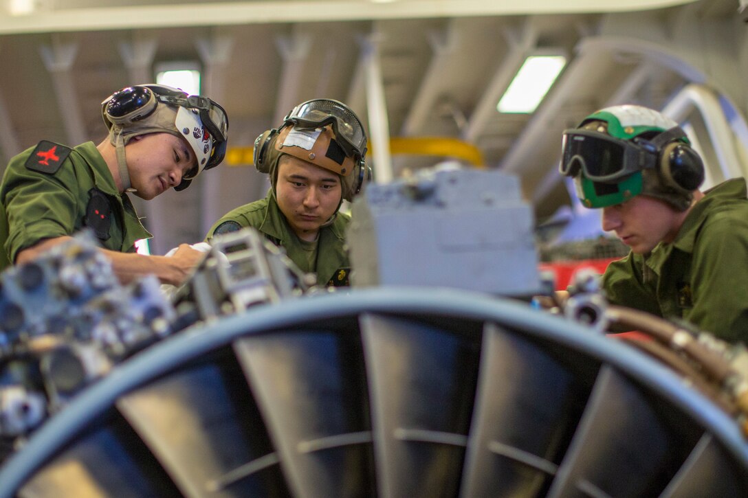 Three Marines work on an aircraft.