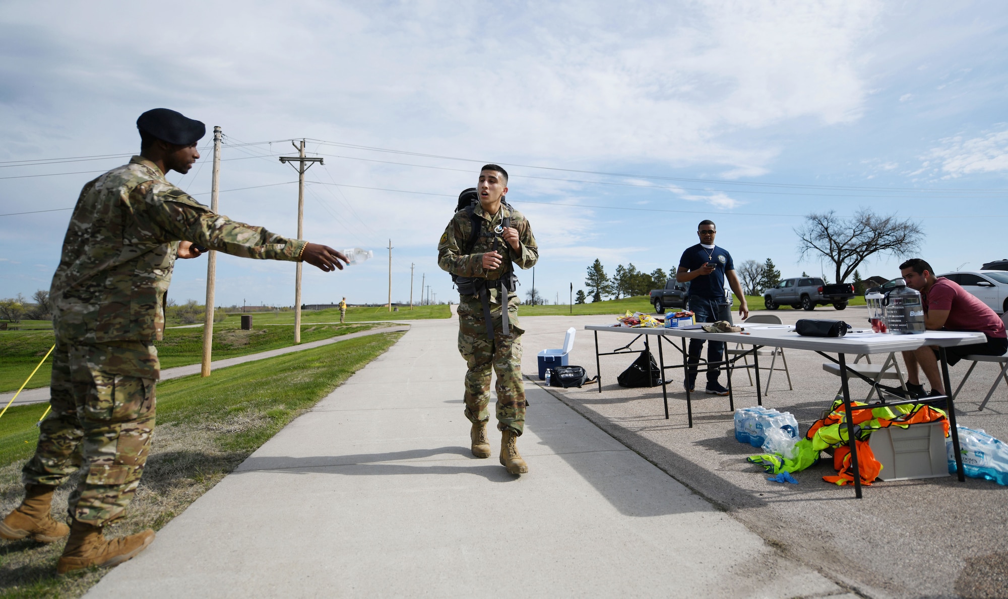 Senior Airman Charles Williams, a 28th Security Forces Squadron response force team member, hands water to Senior Airman Michael Sexton, a 28th Munitions Squadron munitions storage crew member, during the Police Week Ruck Challenge at Heritage Lake on Ellsworth Air Force Base, S.D., May 13, 2019.  Sexton competed the ruck in memory of Deputy Mark Stasyuk, of the Sacramento County Sheriff’s Office, and Officer Natalie Corona, of the Davis Police Department, both in California. (U.S. Air Force photo by Airman 1st Class Christina Bennett)