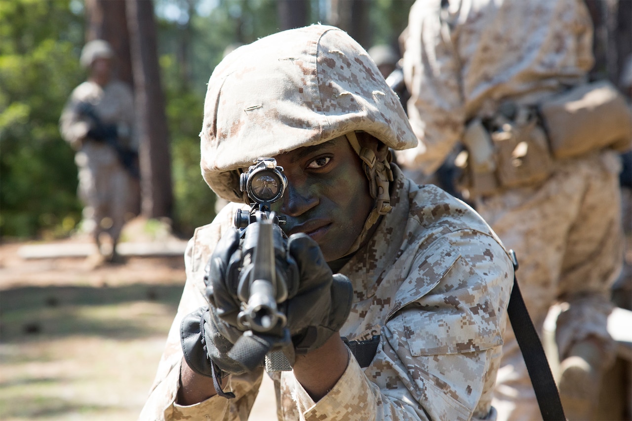 A Marine aims a rifle.