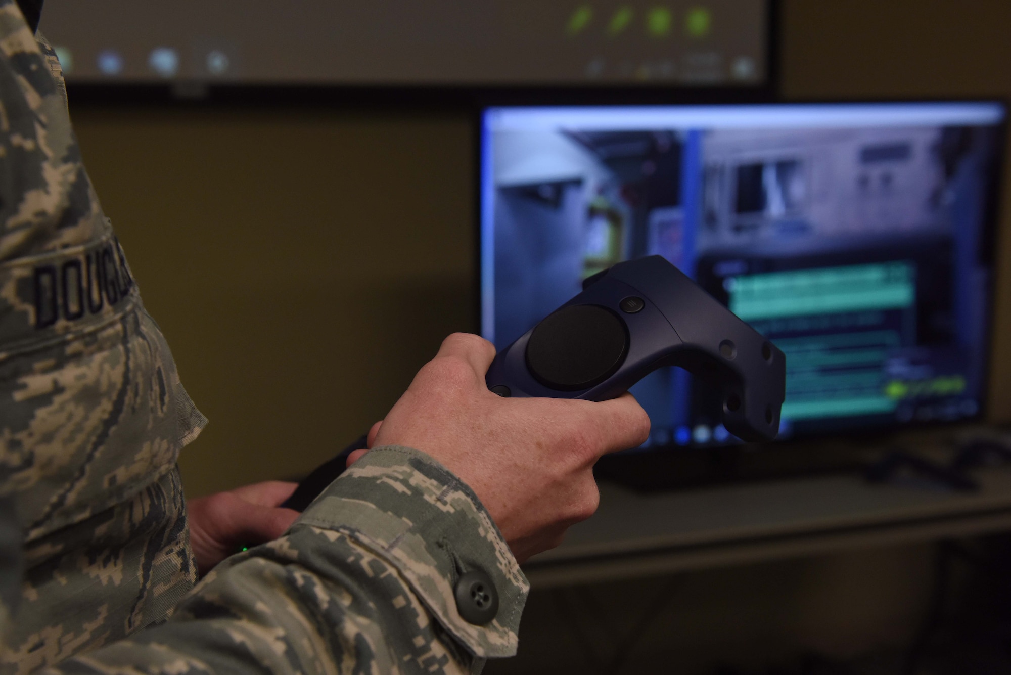 A closeup photo of someone wearing an Airman Battle Uniform holding a virtual reality controller