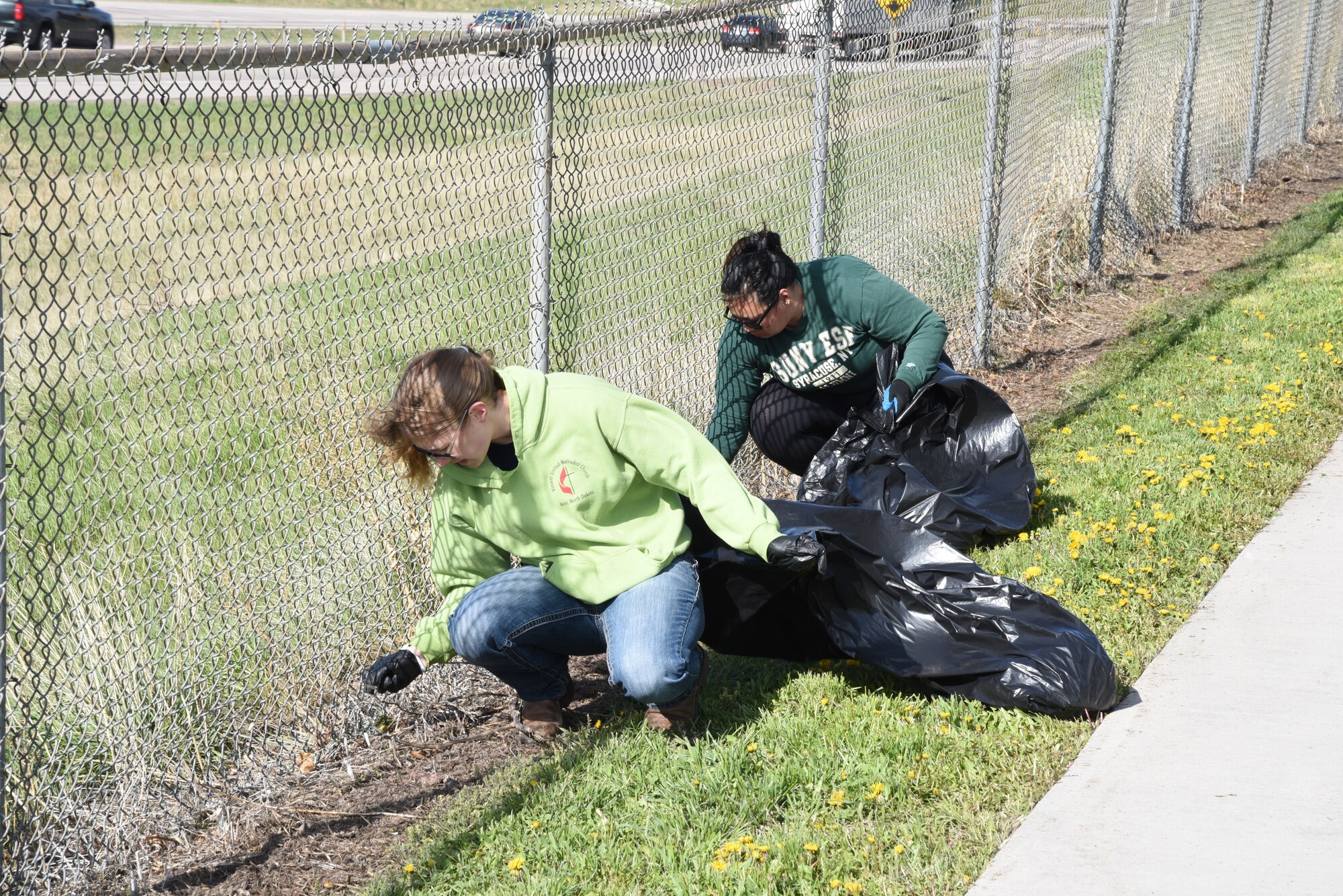 Cpl. Sierra Tryon of the Wyoming National Guard and member of Laramie County Community College's Student Veteran Association and Nicole Ng, Air and Water Program Manager for the 90th Missile Wing, clean a section of fence along the Cheyenne Greenway in Cheyenne, Wyo., May 11. More than fifty volunteers came out as part of the Crow Creek Revival project aimed at bringing the creek closer to its original state.