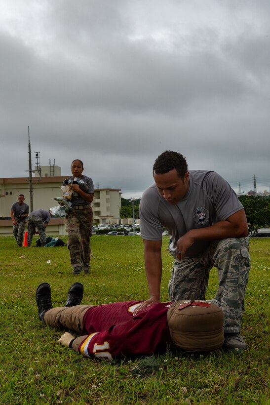 U.S. Air Force Master Sgt. Aaron Waddy, 18th Force Support Squadron first sergeant, applies pressure to a fake wound during the Self-Aid Buddy Care portion of the Shogun Challenge for the 2019 Police Week May 14, on Kadena Air Base, Japan.