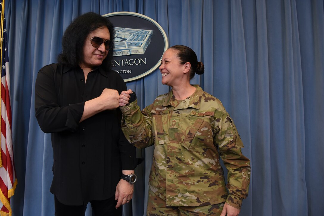 Famous musician Gene Simmons fist-bumps a service member on the stage in the pentagon briefing room.