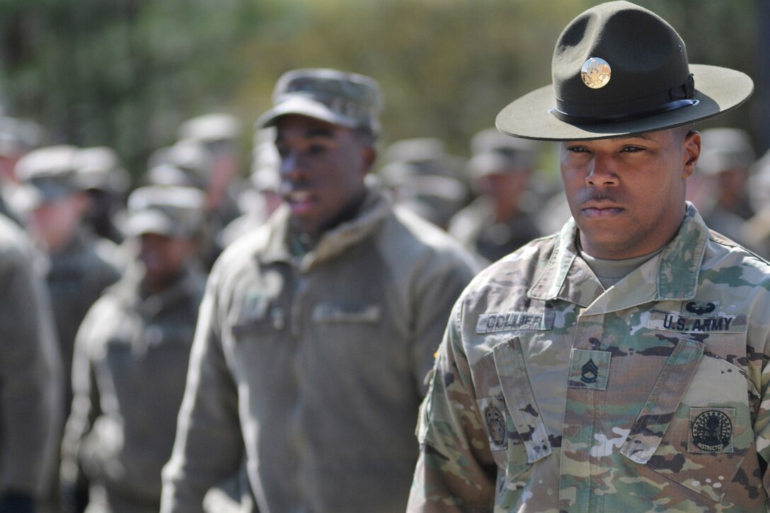 A drill sergeant stands in front of a formation.