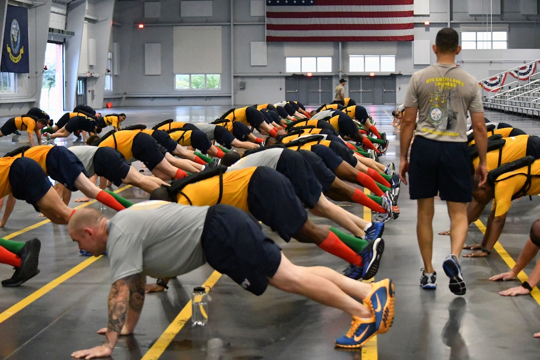 Sailors do pushups in a training bay.