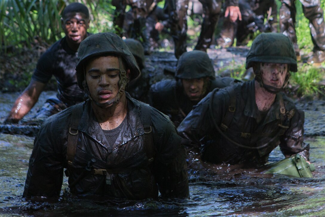 Marines and sailors move through water during an endurance course.