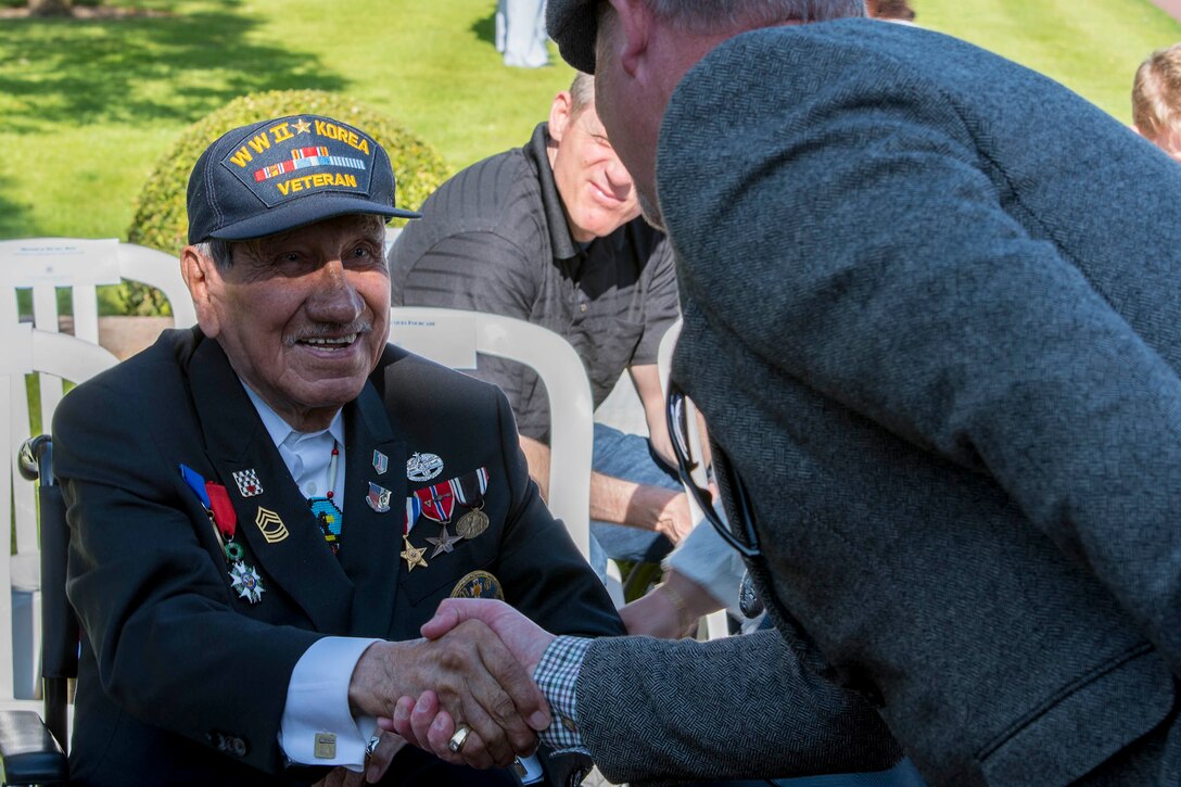 WWII veteran shakes hands with guests.
