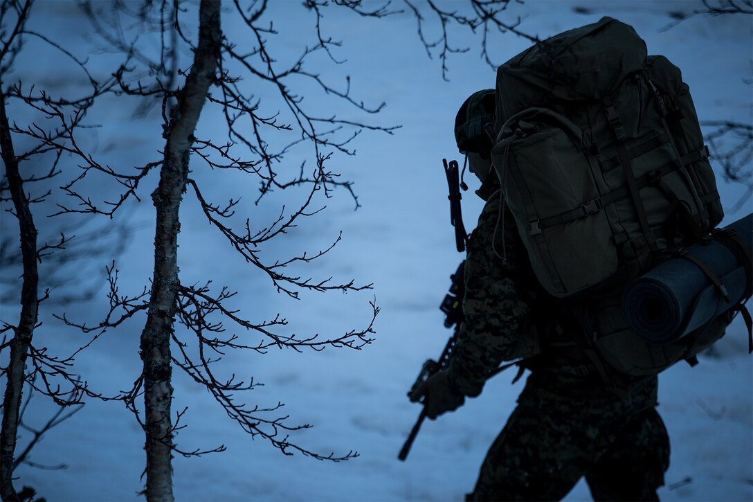 A Marine patrols in the mountains at night.
