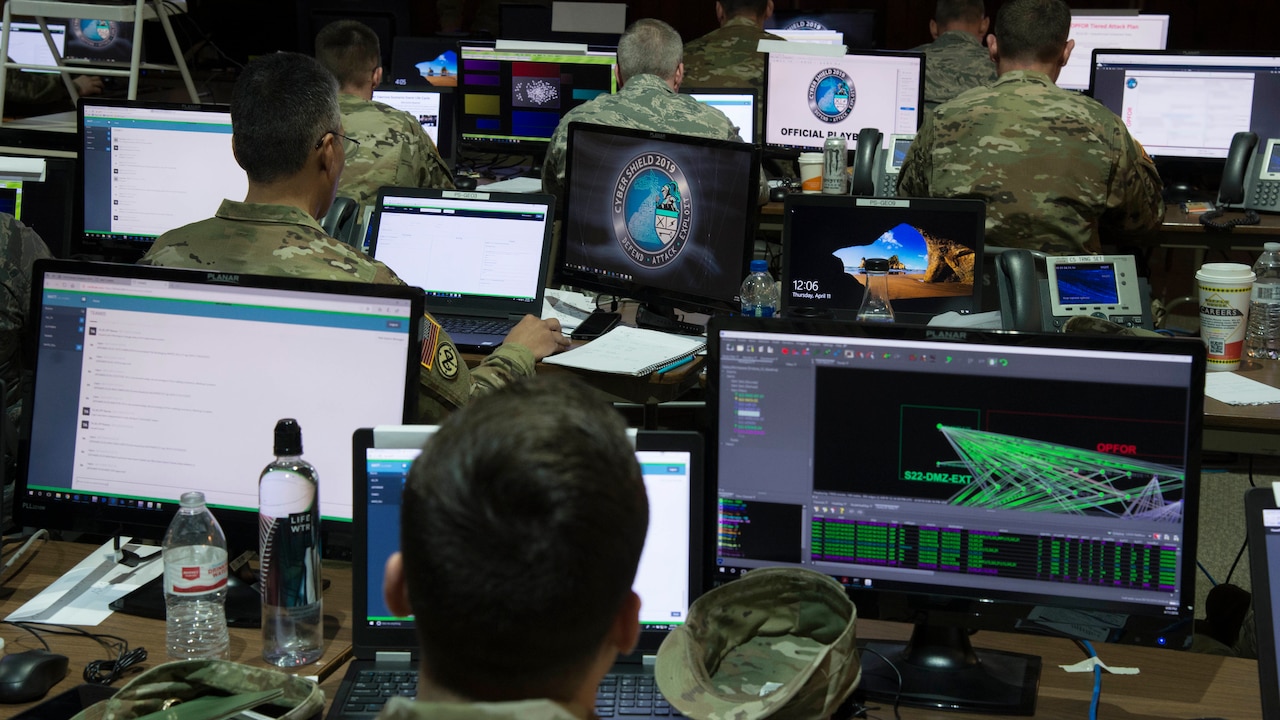 Service members sit at computer screens.