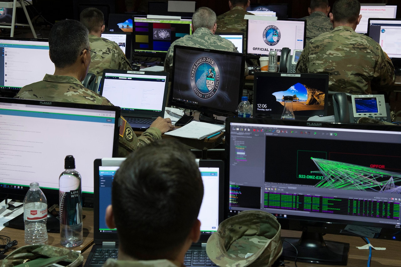 Service members sit at computer screens.