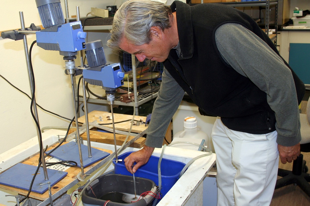 The head of the Environmental Sciences Branch Space at the Naval Warfare Systems Center checks fuel cells in a container.