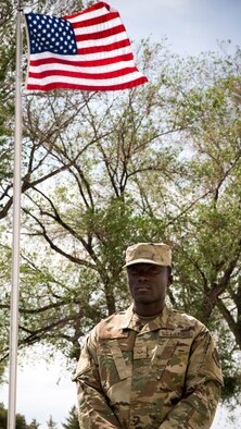 Senior Airman Jalen Thompson, 366th Maintenance Squadron aerospace ground equipment mechanic, stands by the American flag May 14, 2019, at Mountain Home Air Force Base. Thompson recently was awarded entry into the Airman Scholarship Commissioning Program that will pay for his college to become an officer in U.S. Air Force.