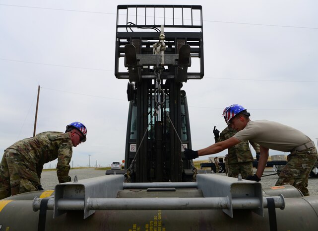 A photo of Airmen attaching a munition to a forklift.