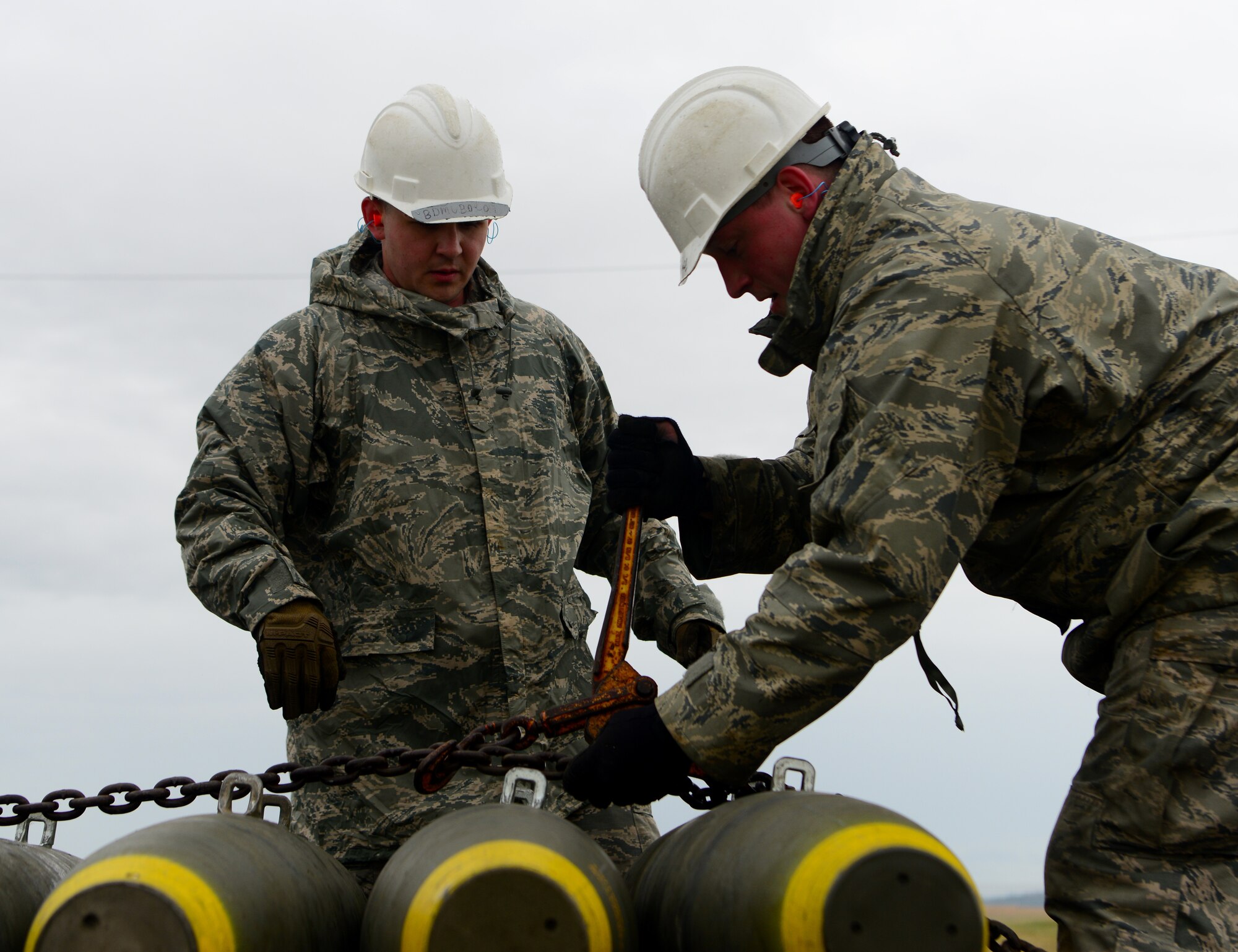 A photo of two Airmen tightening a chain on Beale.