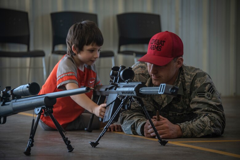 U.S. Air Force Senior Airman John Noble, a Combat Arms instructor assigned to the 97th Security Forces Squadron, shows a child of the Altus community proper weapon technique, May 14, 2019, at Altus, Okla. For weapons like this, Combat Arms travels to Fort Sill to utilize their shooting range that can handle larger caliber weapons. (U.S. Air Force photo by Senior Airman Cody Dowell)