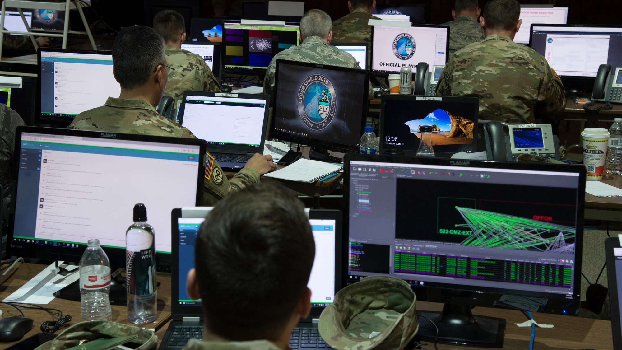 Service members sit at computer screens.